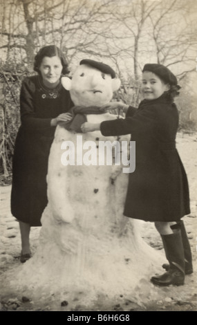 Mutter und Kind einen Schneemann bauen gemeinsam in den 1930er oder 1940er, Zeitvertreib, Großbritannien Stockfoto