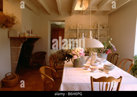 Weiße Pendelleuchten über Tisch mit weißem Tuch und Vasen mit frischen Blumen im Land Speisesaal Stockfoto