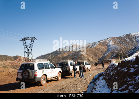 Touristen und 4 x 4 Offroad-Fahrzeuge auf unbefestigten Straße durch hohen Atlas-Gebirge im Winter. Marokko Stockfoto