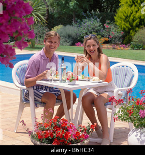 Junges Paar Salat essen und Wein trinken, Pool Stockfoto