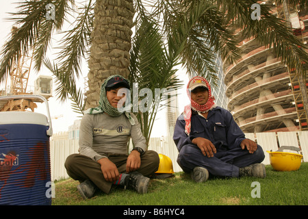 Migrant Bauarbeiter, die Pause unter Palme Baustelle, Doha, Qatar Stockfoto