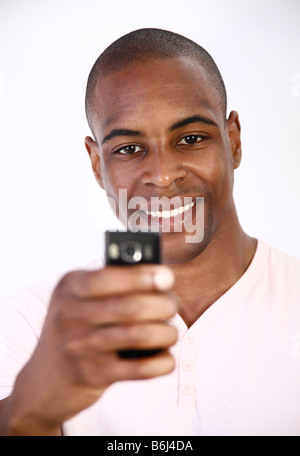 junger Mann lächelnd mit Handy Stockfoto