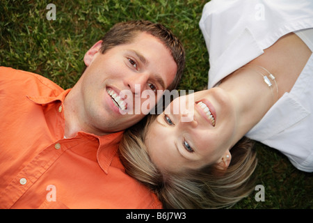 junge weiße Brautpaar liegend auf dem Rasen Stockfoto