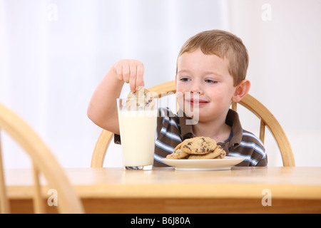 Kleiner Junge Cookie in Glas Milch eintauchen Stockfoto