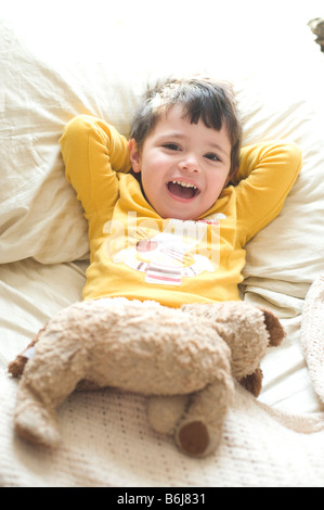 Drei Jahre alten Jungen lounges und spielt im Bett der Eltern Stockfoto