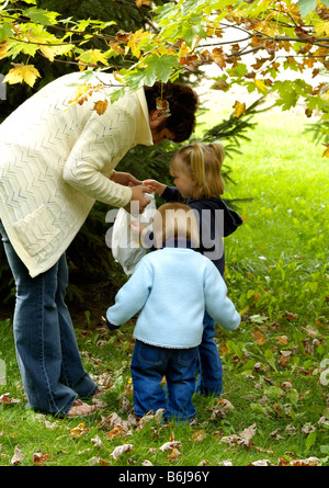 Zwei junge Mädchen laufen um zu entdecken, was Nana in der Tasche hat Stockfoto