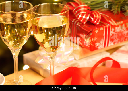 Weihnachts-Szene 2 Weingläser gefüllt mit Weißwein mit verpackte Weihnachtsgeschenke auf Tisch. Stockfoto