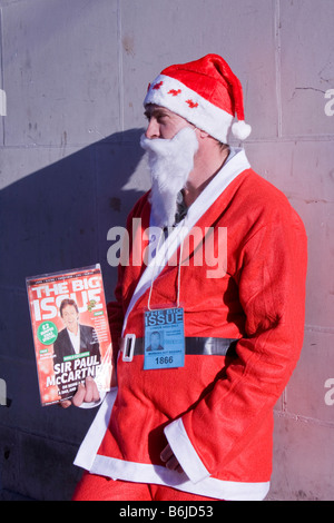 Ein Obdachloser Mann verkleidet als Weihnachtsmann, Verkauf von the Big Issue Magazin in London UK Stockfoto