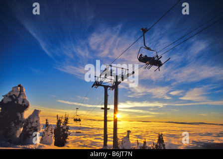 Skifahrer am Sessellift über Inversion Wolken auf Big Mountain Resort in Whitefish, Montana Stockfoto