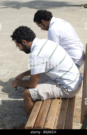 Zwei Männer sitzen nebeneinander auf einer Bank im freien Stockfoto