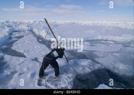 Inupiaq Subsistenz Jäger öffnet ein Loch in das Packeis für potentielle Tierwelt Tschuktschensee passieren Stockfoto