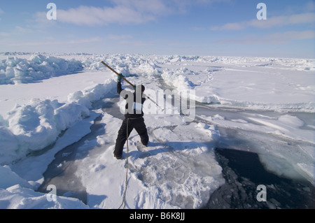 Inupiaq Subsistenz Jäger öffnet ein Loch in das Packeis für potentielle Tierwelt Tschuktschensee passieren Stockfoto