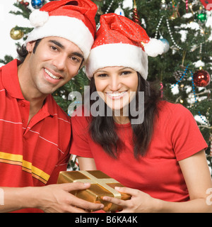 Porträt von ein paar holding ein Weihnachtsfest vorhanden und lächelnd Stockfoto