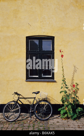 Ein Fahrrad- und Blume vor einem Gebäude mit der charakteristischen gelben Farbe der hübschen Dänischen Dorf Dragør, Kopenhagen, Dänemark Stockfoto