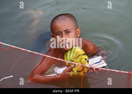 Lokalen Jungen schwimmen und verkaufen einige Bananen in Chong Kneas schwimmendes Dorf auf dem Tonlè-Sap-See, Kambodscha Stockfoto