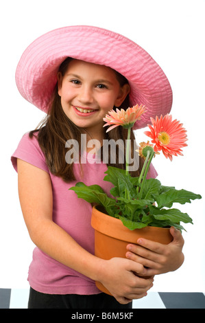 junges Mädchen mit einem rosa Hut und rosa Gänseblümchen in einem Blumentopf Stockfoto