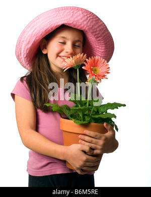 junges Mädchen mit einem rosa Hut und rosa Gänseblümchen in einem Blumentopf Stockfoto