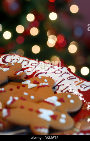 Lebkuchenmänner angeordnet auf einem Teller vor einem Weihnachtsbaum, geringe Schärfentiefe. Stockfoto