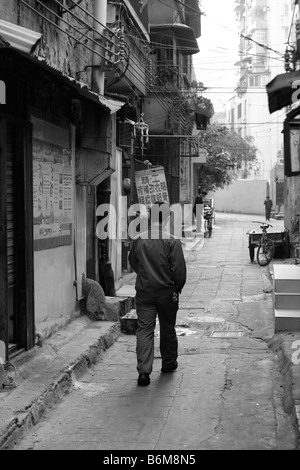 Mann allein zu Fuß in Morgen Seitenstraße Gasse in Guangzhou China Blask und weiße chinesische Zeichen Stockfoto