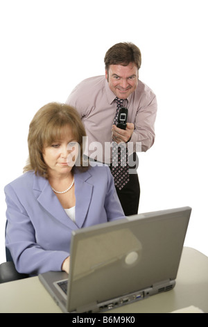 Ein Mann mit einem Kamera-Handy Fotografieren eines Mitarbeiters s Computerbildschirm hinter ihrem Rücken isoliert auf weiss mit Fokus auf den Menschen Stockfoto