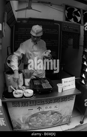 Ein junger Mann bereitet das Frühstück in der ersten kalten Wintermorgen für Pendler auf eine Seite Straße Og Guangzhou Guangdong vorbei Stockfoto