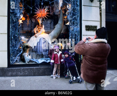 New York Abend 5th Avenue Familie Schaufensterbummel. Vater fotografiert seine Familie auf der Fifth Avenue vor dem Kaufhaus Bergdorf Goodman. USA Stockfoto