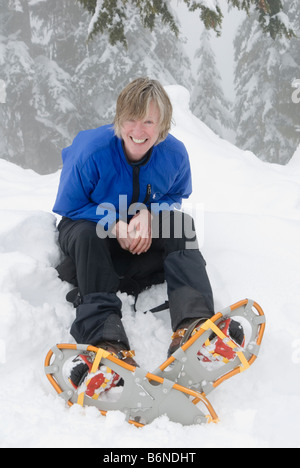 Fröhliche aktive mittlere gealterte Frau außerhalb im Winter mit Schneeschuhen Stockfoto