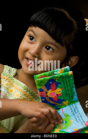 Hispanischen Mädchen hält ein Spielzeug-Buch Stockfoto