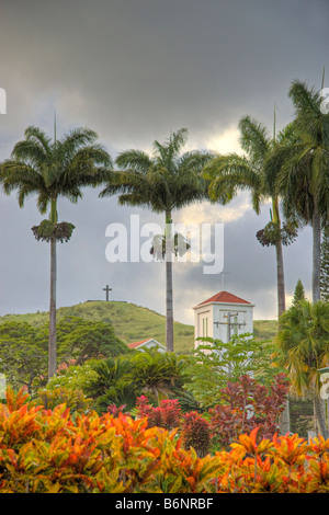 Str. Marys katholische Kirche Kreuz vor dem Lavagestein Kreuz auf einem grasbewachsenen Hügel mit Blick auf Stadt Hana, Maui, Hawaii. Stockfoto
