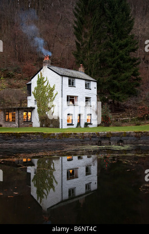 Weißes Haus mit Rauch aus Schornstein spiegelt sich im Kanal Llanfoist Wales UK Stockfoto