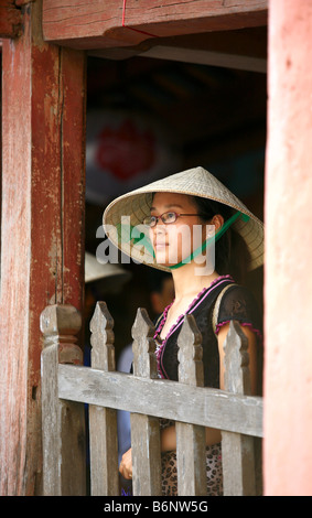 Vietnamesisches Mädchen mit Blick vom hölzernen Fensterrahmen Stockfoto