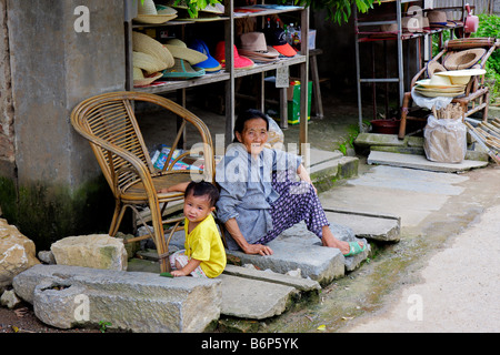 Eine alte chinesische Frau mit einem kleinen Kind sitzen vor ihren Shop, Yangshuo, Region Guangxi, China Stockfoto