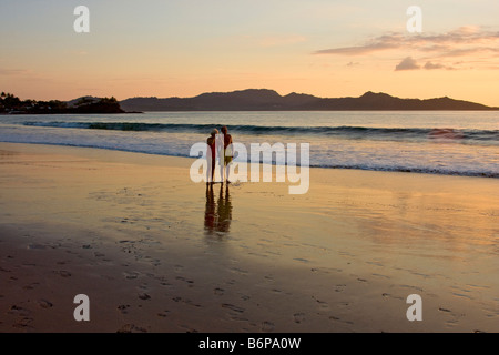 Paar genießt zu Fuß am Strand entlang zum Sonnenuntergang entlang Flamingo Beach in Costa Rica Stockfoto