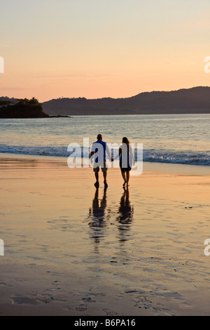 Paar genießt zu Fuß am Strand entlang zum Sonnenuntergang entlang Flamingo Beach in Costa Rica Stockfoto