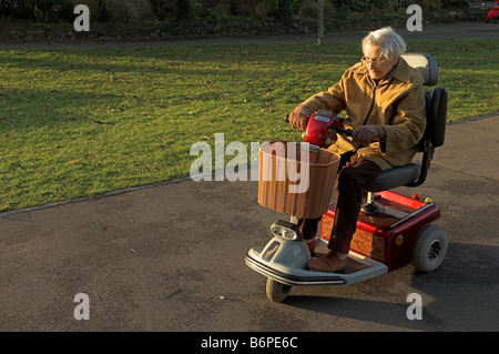 Ältere Frau auf ungültige Elektroroller auf Ausflug im Winter Nachmittagssonne Stockfoto