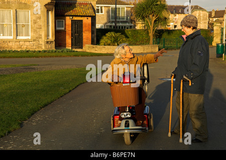 Ältere Menschen und Mitte im Alter von Frauen mit Behinderungen während am Nachmittag Ausflug ein Winter Weston Super Mare North Somerset England sprechen Stockfoto