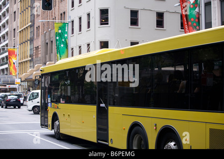 gelbe kurvenreich Bus bewegt sich entlang der York Street und die Weihnachts-Banner hängen dort, Sydney, Australien Stockfoto