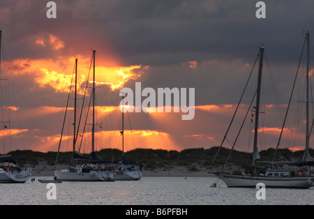 Die Sonne zwischen den Wolken hinter die Schiffe in der Insel Espalmador, einer kleinen Insel auf den Balearen verankert Stockfoto