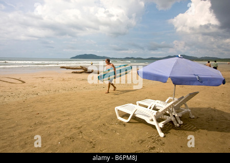 Surfer geht auf Strand in Tamarindo, Costa Rica. Costa Rica ist eine beliebte Surf-Standort geworden. Stockfoto