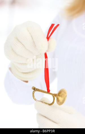 Hände mit Winterhandschuhe mit goldenen Trompete Weihnachtsbaum ornament Stockfoto