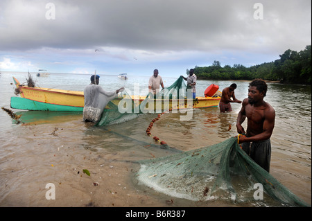 HANDWERKLICHE FISCHER SÄUBERN IHRE NETZE AM STRAND IM MORGAN BAY RESORT IN DER NÄHE VON CASTRIES, ST. LUCIA Stockfoto