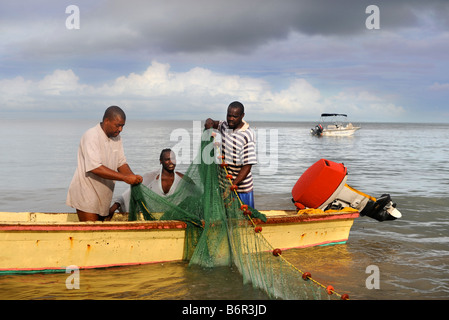 HANDWERKLICHE FISCHER SÄUBERN IHRE NETZE AM STRAND IM MORGAN BAY RESORT IN DER NÄHE VON CASTRIES, ST. LUCIA Stockfoto