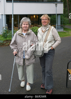 mittelalterlichen Frau helfen, ihre Mutter mit einem Spaziergang in einer Straße Stockfoto