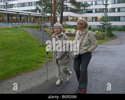 mittelalterlichen Frau helfen, ihre Mutter mit einem Spaziergang in einer Straße Stockfoto