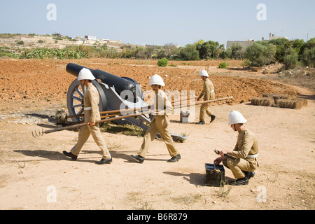 Soldaten tragen der Ausrüstung in einem Feld nach Kanone abfeuern, Fort Rinella Kalkara, Malta Stockfoto