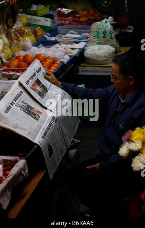 Chinesische Ladenbesitzer, lesen die neuesten Schlagzeilen in Guangzhou Guangdong China die Schlagzeilen sind über Gaspreise Stockfoto