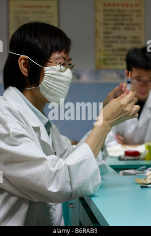 Chinesische Krankenschwester sieht man Schuss in Guangzhou Guangdong China vorbereiten. Chinesische Krankenschwestern Ärzte sitzen um Tabelle der lokalen hea Stockfoto