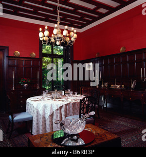 Beleuchtete Kronleuchter oben runder Tisch mit weißen Tuch im roten Speisesaal mit der Hälfte der Verkleidung Stockfoto