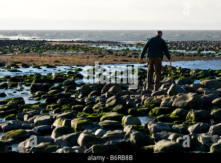 Eine Person, die zu Fuß über den Strand in Llantwit Major Vale of Glamorgan in Südwales. Stockfoto