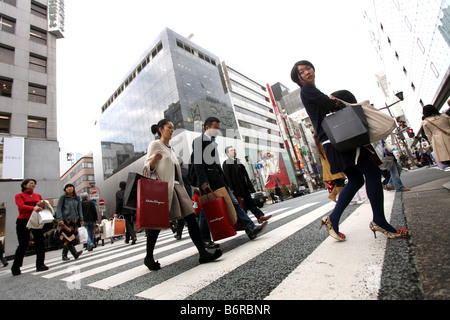 Shopper überqueren Sie die Straße, halten ihre Designer Shopping-Taschen in Ginza, Tokio Japan Stockfoto
